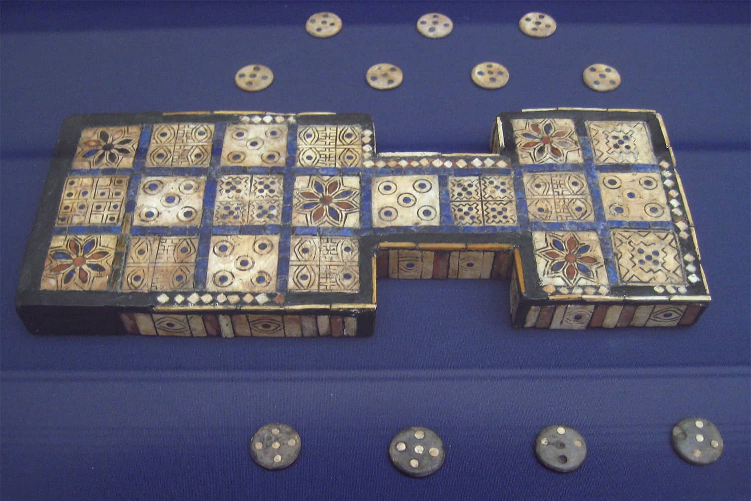 An ancient Royal Game of Ur board displayed with game pieces and dice.
