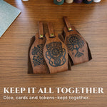 Three brown Norse belt pouches with different engraved mythic designs on a wooden table.