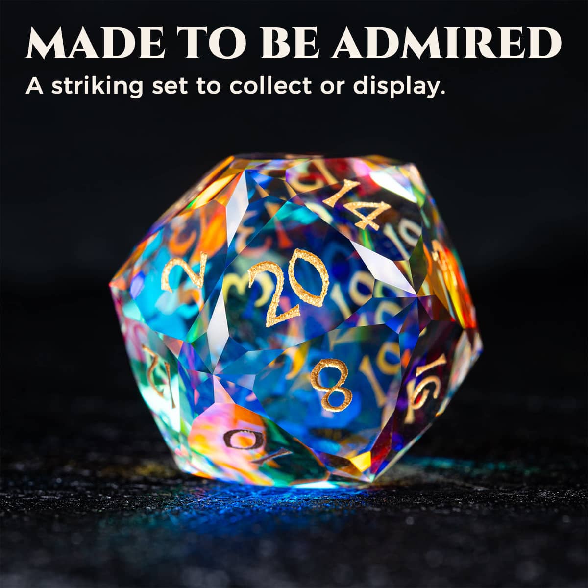 Rainbow-reflective glass D20 with gold-tone numbers on a dark surface, under a Made to Be Admired heading.