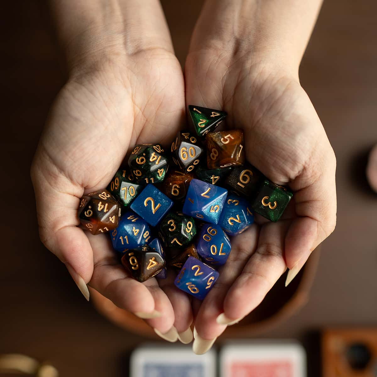 Cupped hands holding a collection of colorful polyhedral dice.