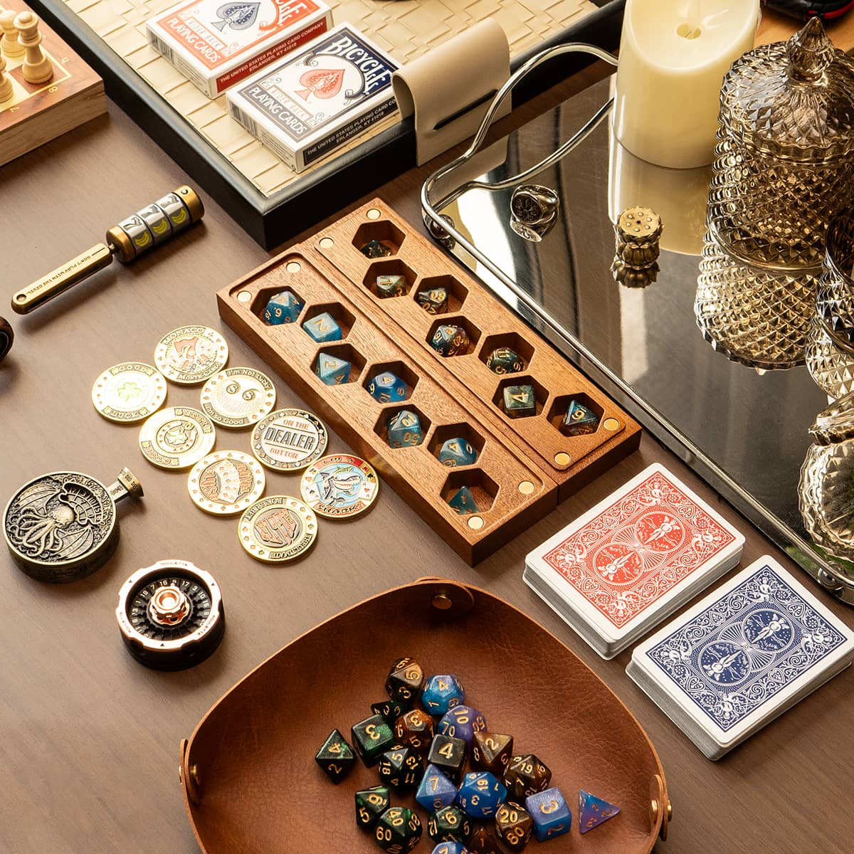 Wooden dice boxes, colorful polyhedral dice, playing cards and metal game accessories on a tabletop.