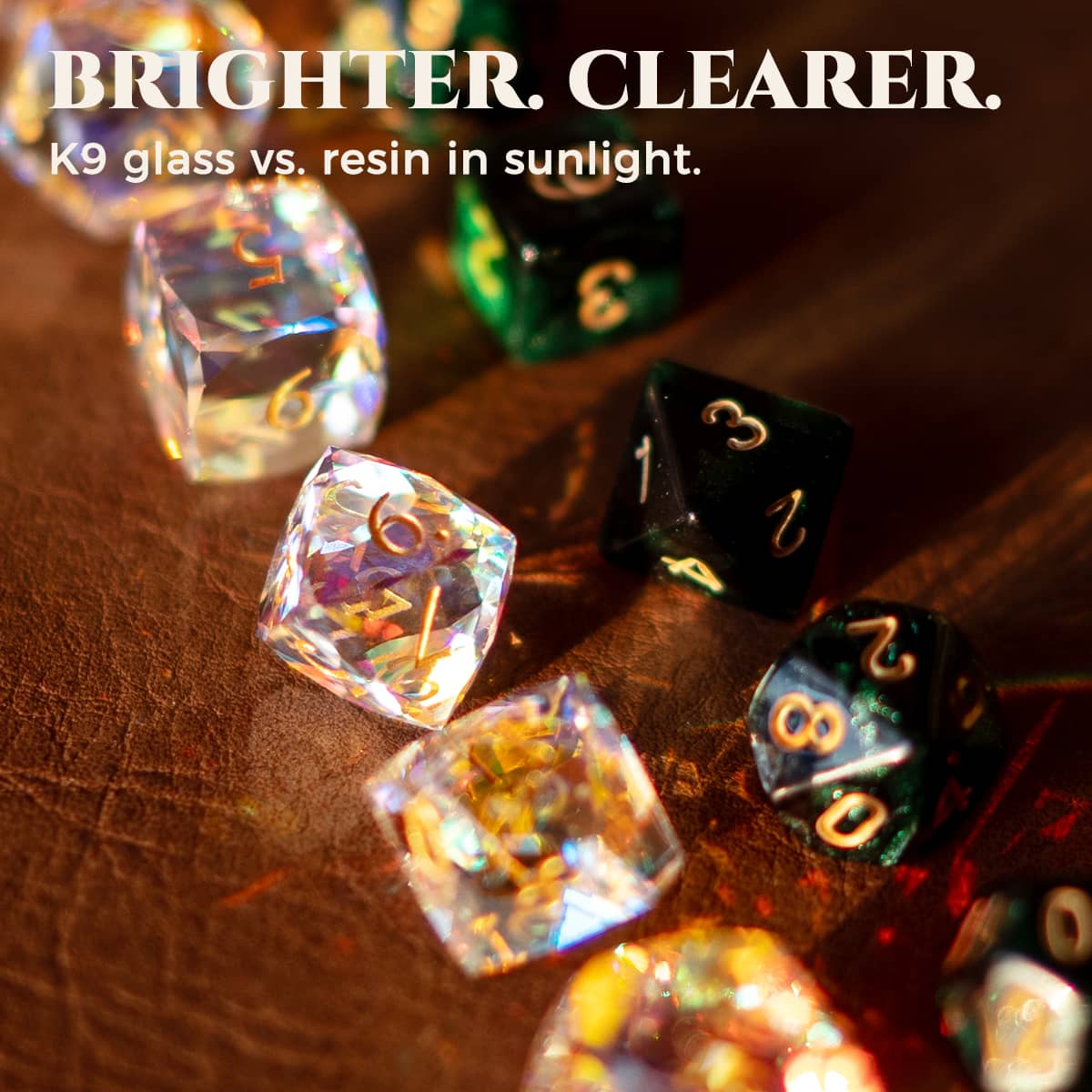 Rainbow-reflective K9 glass dice and dark resin dice shown in sunlight.